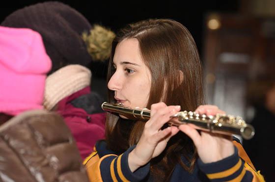 Photo of a student in a band uniform playing the flute outside